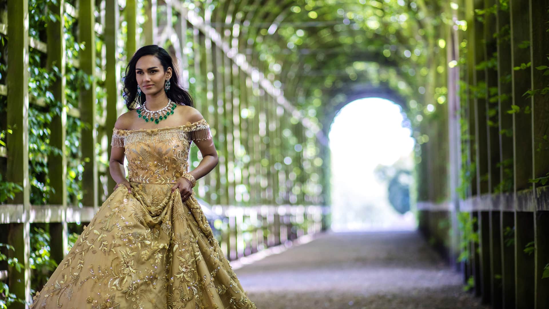 Asian Wedding Photoshoot in the Garden, walkway on the south front, Queen Mary's Bower. Back lit bride wearing gold.